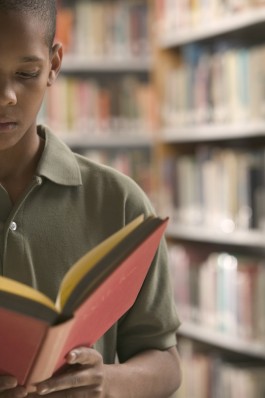 Boy Reading Book in a Library
